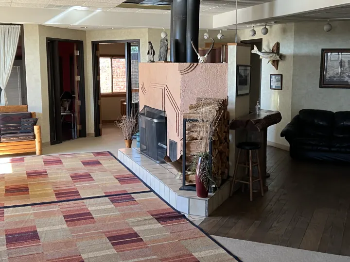 Central lodge fireplace with stacked firewood and seating, photographed in 2022