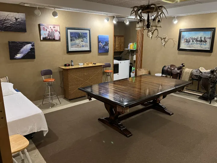 Lodge game room with a large table, saddles, and ranch artwork, photographed in 2022