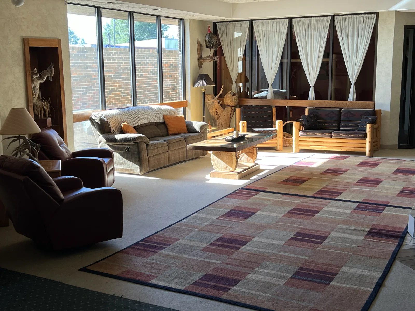 The lodge gathering room with sofas, a coffee table, and broad windows, photographed in 2022