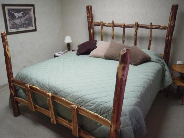 Archival lodge bedroom with a natural wood bedframe and pale green bedding