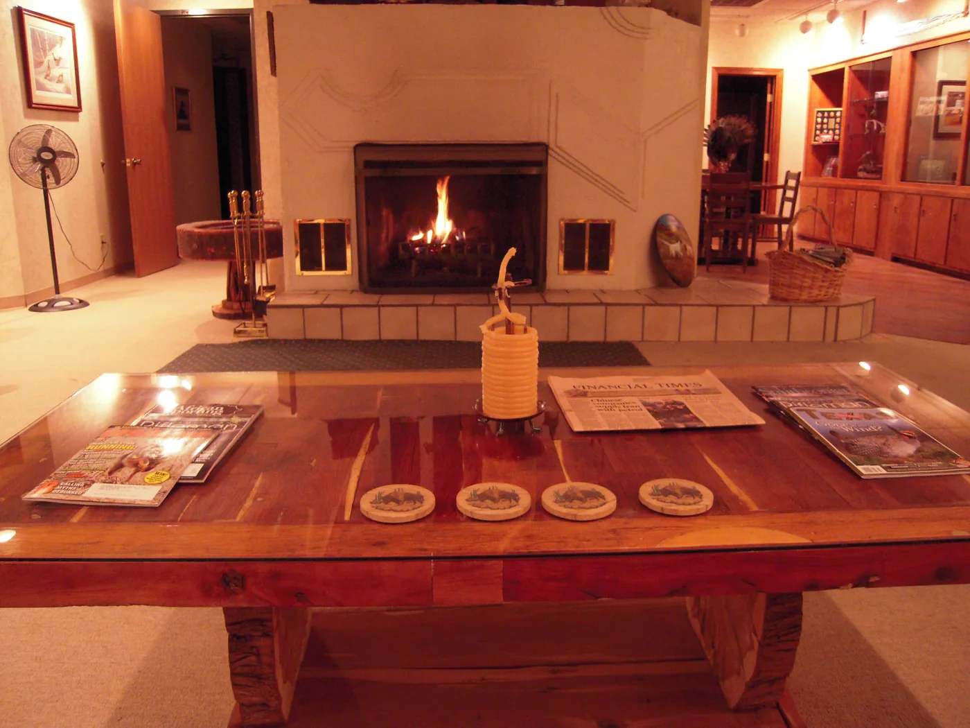 Archival lodge photograph of a glowing fireplace and a wooden gathering table
